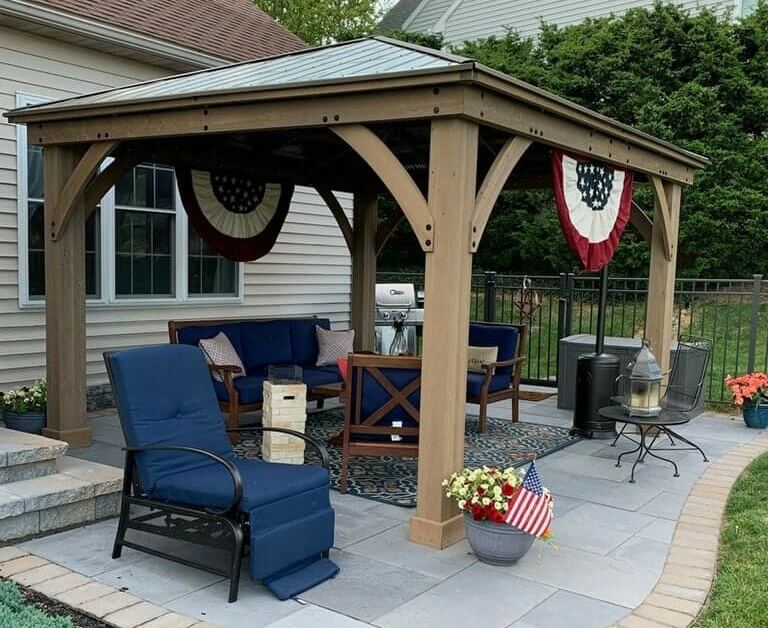 light stone patio with light brick border and a pavillion over some chairs