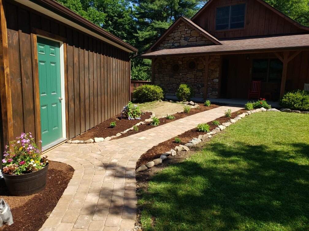 brick pathway connecting the back porch of a log cabin to a wood storage shed