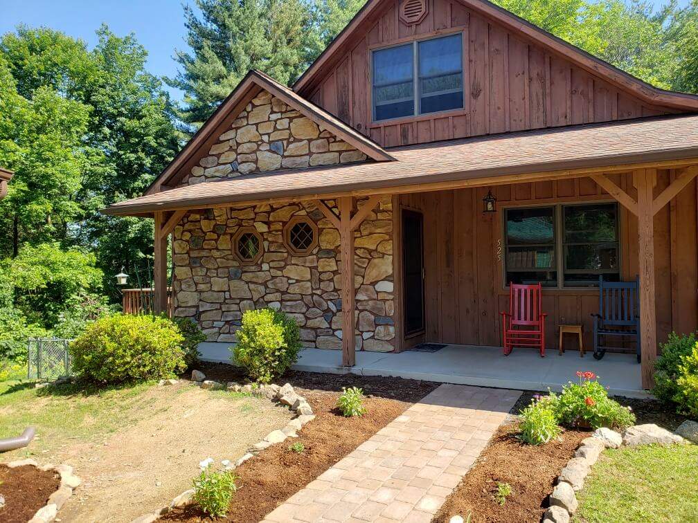 backyard brick path leading up to a log cabin home with stone accent wall