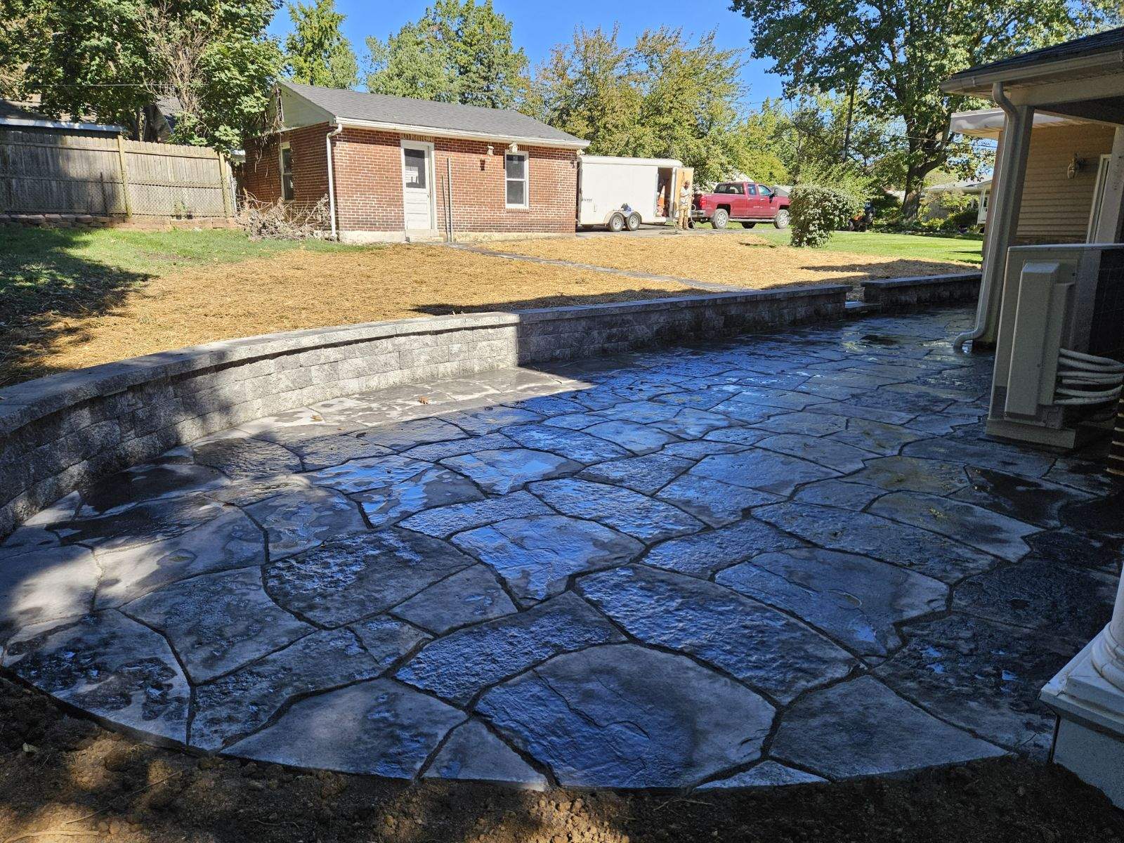 stone patio with grey brick walls around it expanding on the old patio